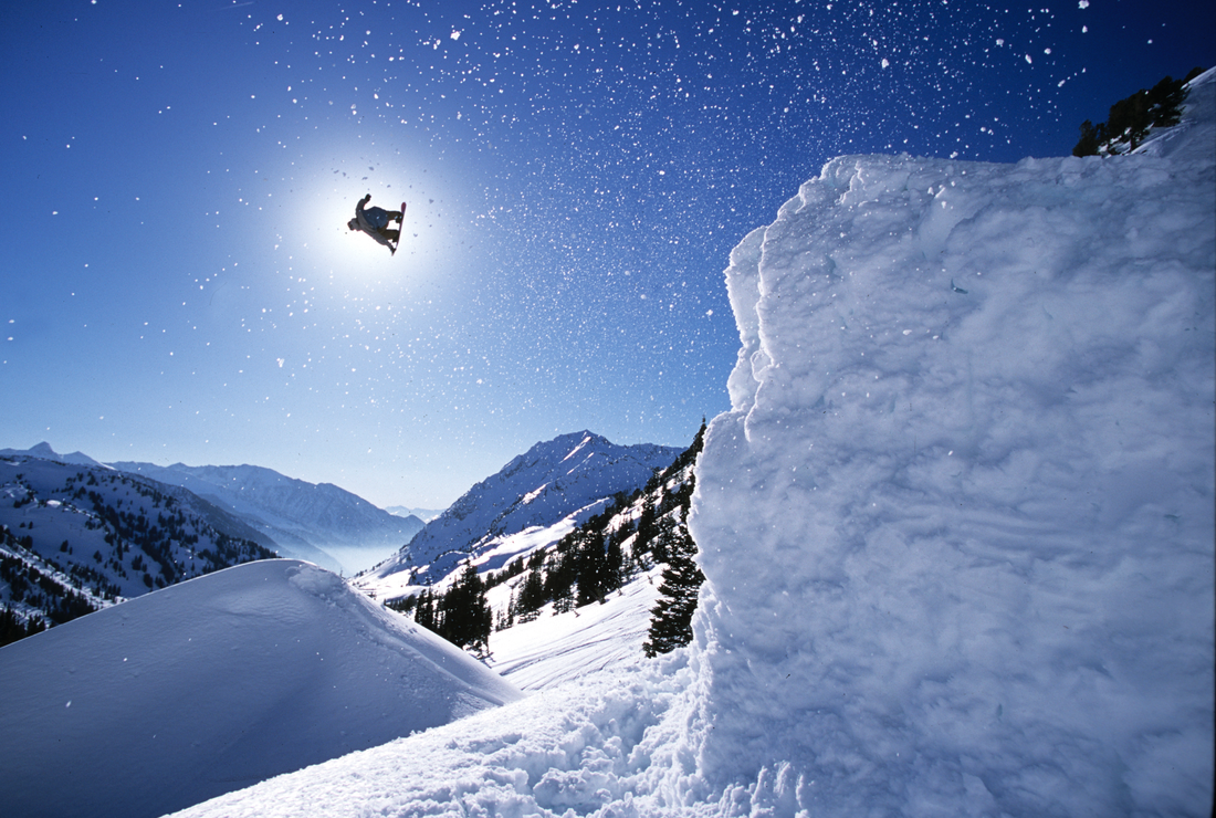 Snowboarder Romain De Marchi eclipses the sun as he goes off a massive jump